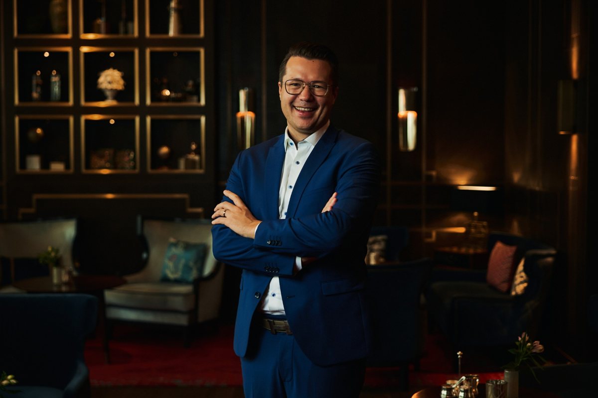 Dr. Paul Littau mit verschränkten Armen in einer Hotel-Lounge