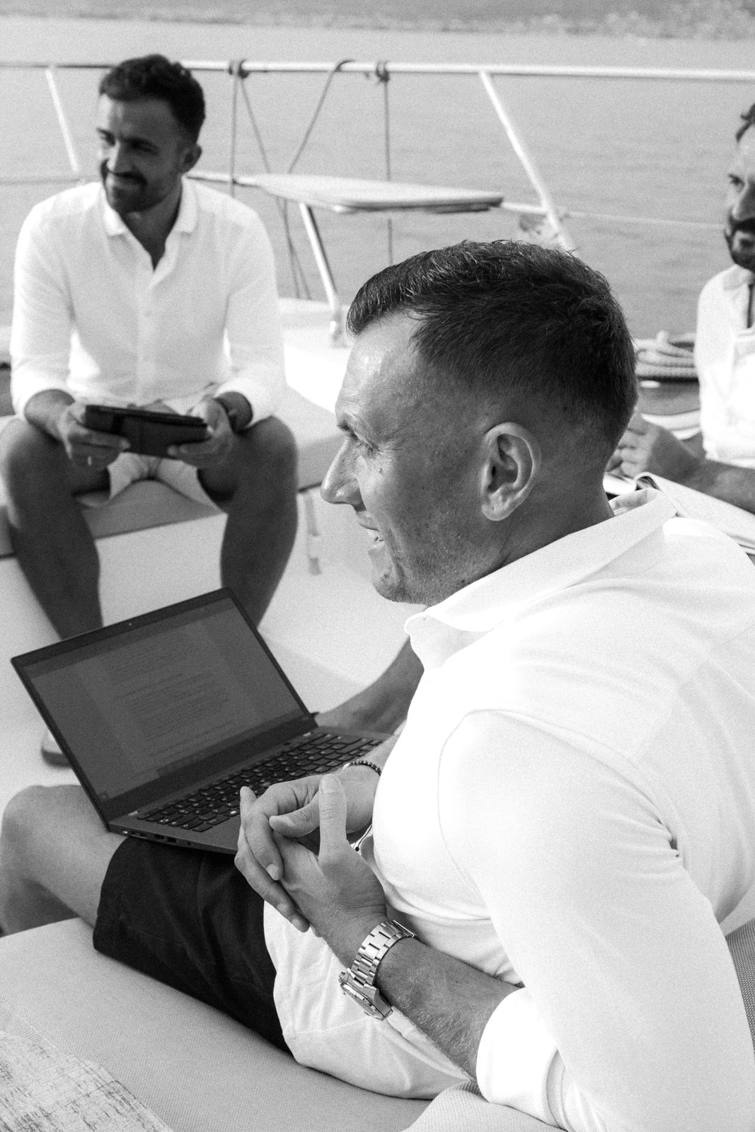 Zwei Teilnehmer der Yacht Mastermind im Gespräch an Deck, einer mit Laptop